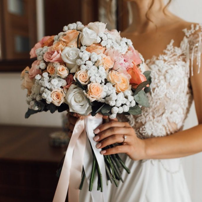 Bride holds the lush bouquet with delicate flowers colors